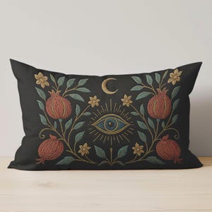 May include: Black rectangular cushion with an embroidered design. The design includes pomegranates, flowers, leaves, a crescent moon, and an eye, in red, gold, blue, and green. Suitable for home decor.