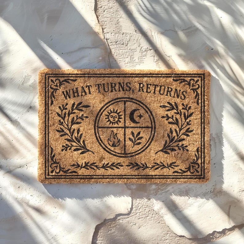May include: Rectangular coir doormat with the text "WHAT TURNS, RETURNS" in black. The centre features a circular design with sun, moon, fire, and plant symbols. Decorative black leaf patterns frame the text and design.