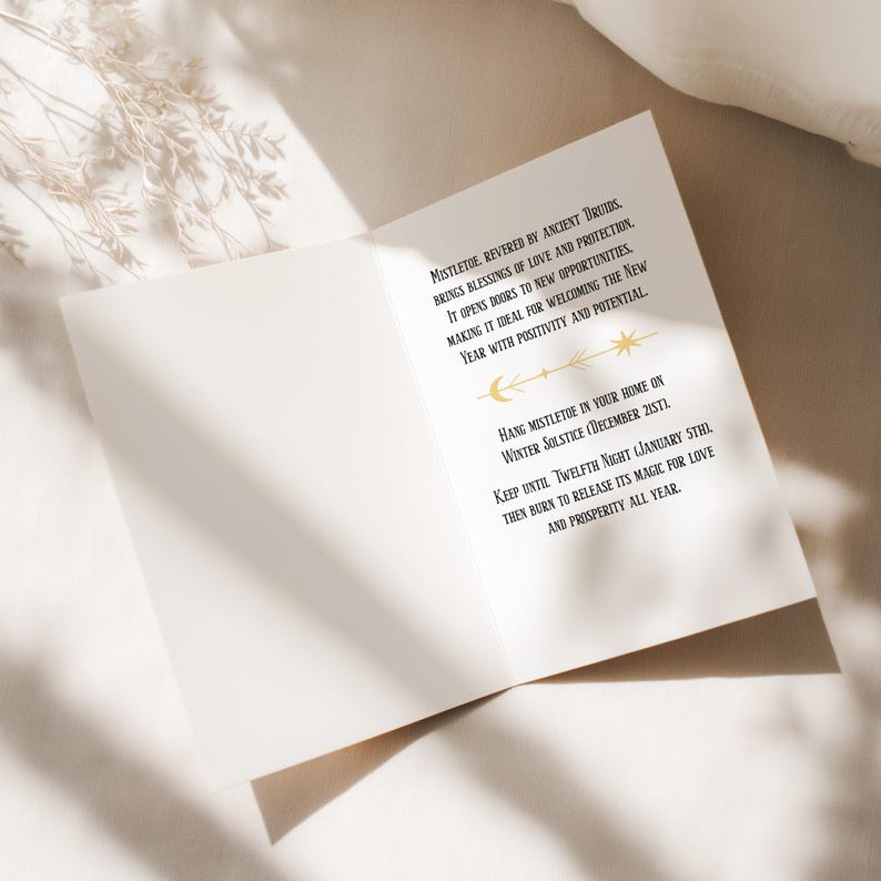 Luxurious black Yule card featuring golden mistletoe design, moon phases, and stars. "Mistletoe" and "For Protection & New Beginnings" in ornate gold text.
