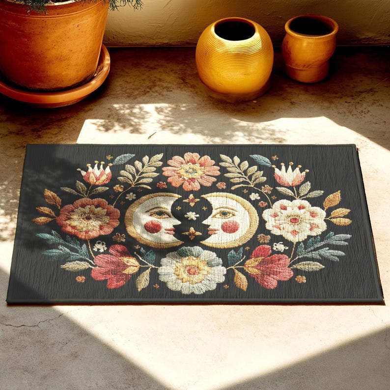 Witchy outdoor doormat featuring a central all-seeing eye, crescent moons, and floral details in an embroidery-style design. This weatherproof welcome mat measures 26x18 inches and is ideal for porches or patio entries. Symbolic celestial motifs offer intuitive protection and spiritual elegance for magical home decor.