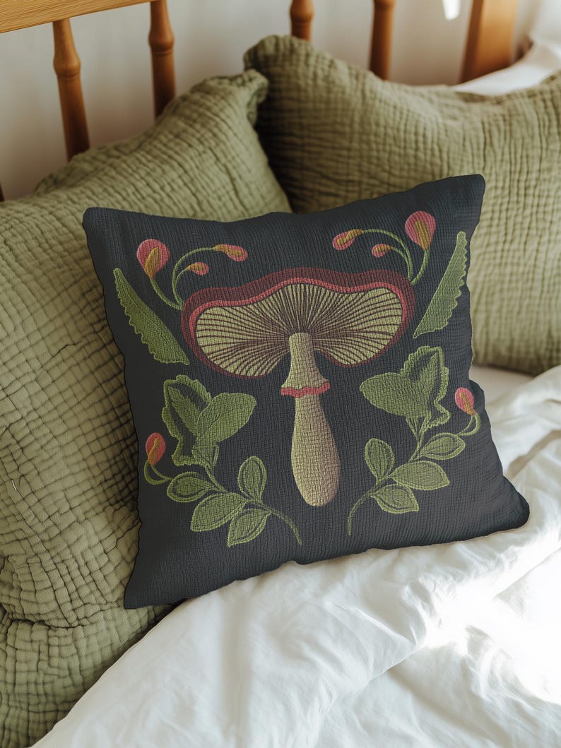 A dark woven pillow with a detailed embroidered mushroom and botanical design in deep red, green, and gold tones. Made with a cotton-poly blend.