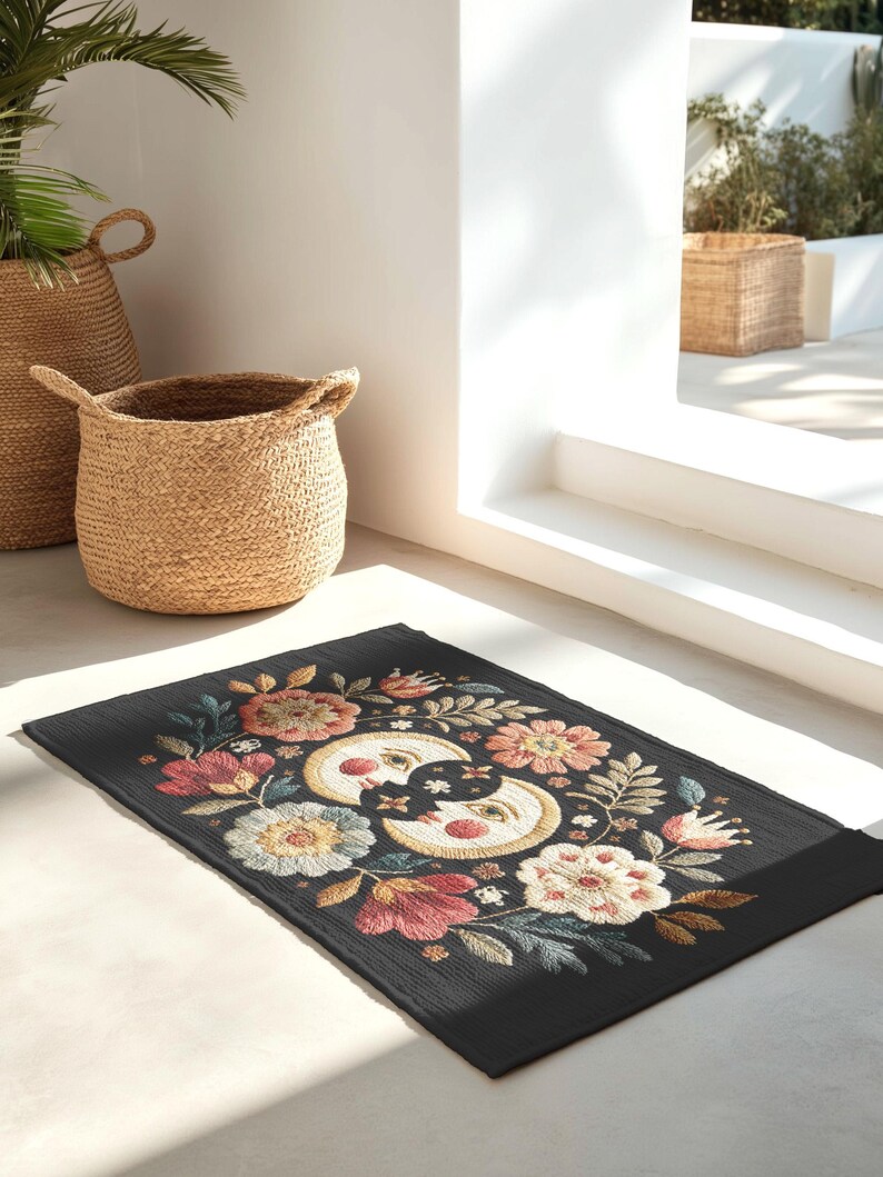 Witchy outdoor doormat featuring a central all-seeing eye, crescent moons, and floral details in an embroidery-style design. This weatherproof welcome mat measures 26x18 inches and is ideal for porches or patio entries. Symbolic celestial motifs offer intuitive protection and spiritual elegance for magical home decor.