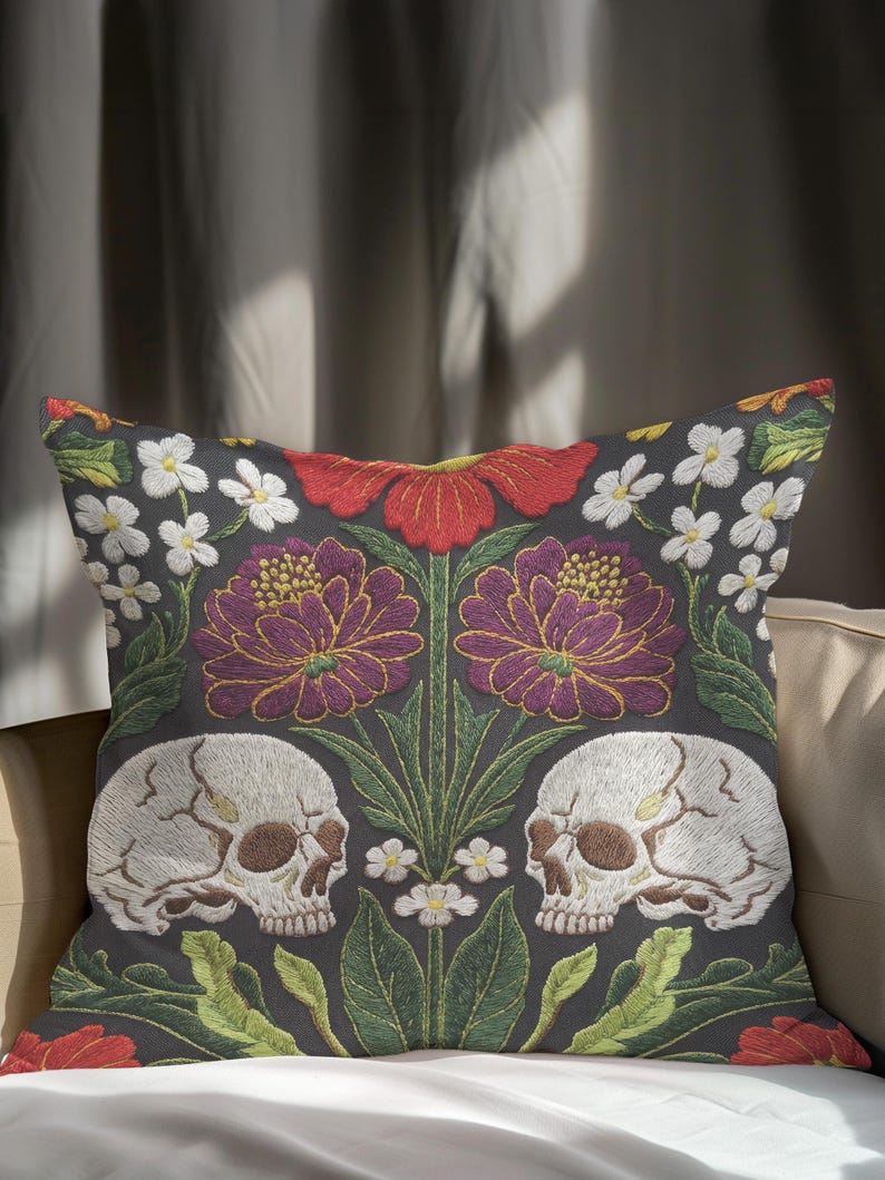 Grimoire and Goblet gothic pillow cover featuring mirrored ivory human skulls surrounded by detailed floral and botanical elements including deep red flowers, purple blooms with gold outlining, small white blossoms, and layered green foliage, arranged in a symmetrical composition on a charcoal background, designed with a high-detail faux embroidery print that mimics stitched texture while remaining smooth, creating a dark academia and gothic botanical aesthetic decorative cushion cover