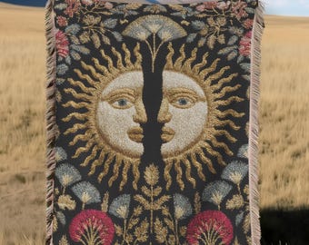 May include: A black tapestry with a sun face design, embroidered with gold thread. The sun has a face with blue eyes. The tapestry is decorated with floral and tree designs in red, blue, and gold. The tapestry is hanging on a clothesline.