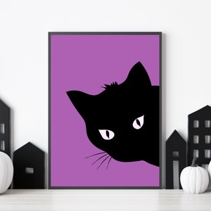 May include: A framed art print featuring a black cat silhouette peeking out from the right side against a purple background. The cat has white eyes and whiskers. Decorative black houses and white pumpkins are in the foreground.