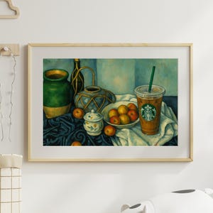 May include: A framed still life painting featuring a green and gold vase, a blue and gold decorative jar, a bowl of apples, and a Starbucks iced coffee. The painting has a blue and white background and a dark blue tablecloth.
