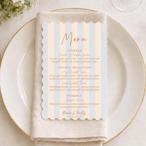 May include: A scalloped-edge menu card featuring vertical light blue and cream stripes with copper-colored text. The menu lists a starter, entree selection, and dessert, ending with the names Giselle & Bradley and the date 10.12.2025.