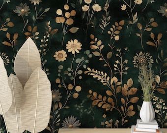 Peut inclure: Papier peint floral vert foncé avec des motifs botaniques dorés et crème. Un panier en osier avec de grandes feuilles décoratives crème est au premier plan. Une table en bois supporte un vase blanc avec de l'herbe séchée et une pile de livres.
