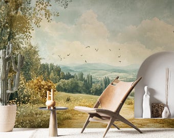 May include: A brown leather chair with a wooden frame sits in front of a wall mural depicting a landscape with trees, hills, and a cloudy sky.