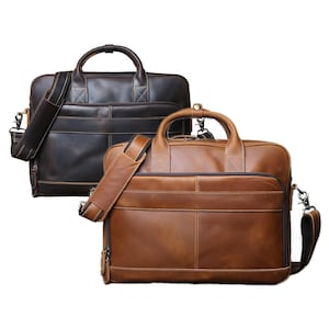 May include: Two leather briefcases in the image. One is dark brown, the other is tan. Both have top handles, shoulder straps, and multiple compartments. The briefcases are designed for carrying documents and other work essentials.