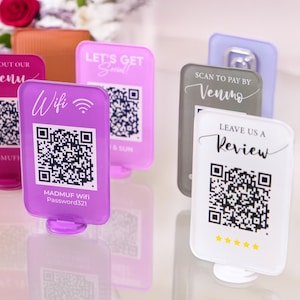 May include: A set of six acrylic table signs with QR codes and text. The signs are in various colours, including pink, purple, white, and grey. The text on the signs includes "Check out our Menu", "Wifi", "Let's Get Social", "Scan to Pay by Venmo", "Leave Us a Review", and "Check out our Menu".