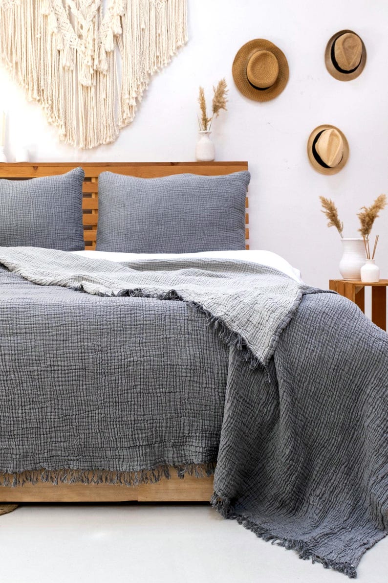 May include: A charcoal gray bedding set featuring a textured, crinkled fabric duvet cover and two matching pillow shams. The duvet cover has a frayed, raw edge fringe detail along the bottom and sides, providing a soft, layered appearance.