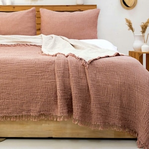 100% Turkish cotton muslin bedspread with a light brick coloured pillowcase on a double bed with a close-up view of the bedspread.