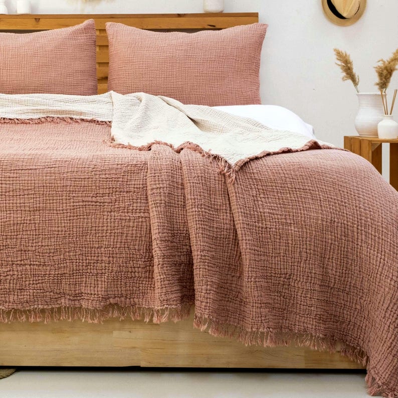 100% Turkish cotton muslin bedspread with a light brick coloured pillowcase on a double bed with a close-up view of the bedspread.