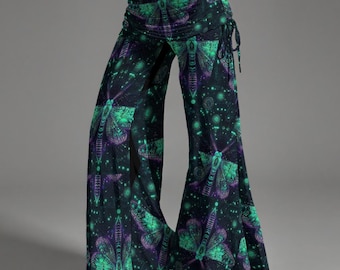 Puede incluir: Pantalones de pierna ancha con un fondo oscuro y un patrón repetitivo de polillas en verde vibrante y morado. Los pantalones presentan un diseño de cintura alta con una banda elástica fruncida y lazos laterales, creando una silueta fluida.