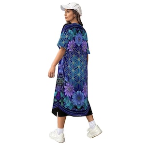 May include: A short-sleeved midi dress featuring a vibrant blue and purple floral pattern with a geometric flower of life design. The garment has a round neckline, a straight hem with side slits, and is paired with a white baseball cap and white sneakers.