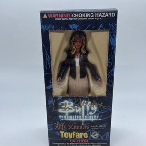 Könnte beinhalten: Eine Buffy Summers Actionfigur aus der Episode Prophecy Girl, verpackt in einer rechteckigen blau-schwarzen Schachtel. Die Figur hat blondes Haar, eine dunkelbraune Jacke, ein weißes Oberteil und einen beigen Rock. Die Verpackung enthält Warnhinweise.