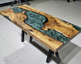 Könnte beinhalten: Ein Holztisch mit einem grünen Epoxidharzfluss, der durch die Mitte verläuft. Der Tisch hat schwarze Metallbeine.