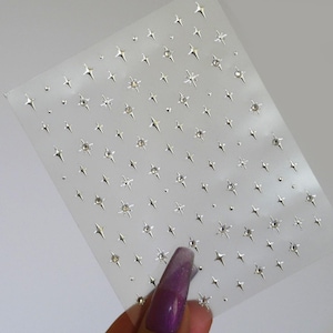 May include: A sheet of clear adhesive-backed paper with a repeating pattern of silver star-shaped rhinestones.