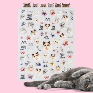 May include: A sheet of cat-themed stickers with various cat faces, flowers, and phrases like "Love" and "Meow." A gray cat is lying on a pink background. The stickers feature different cat breeds and styles.