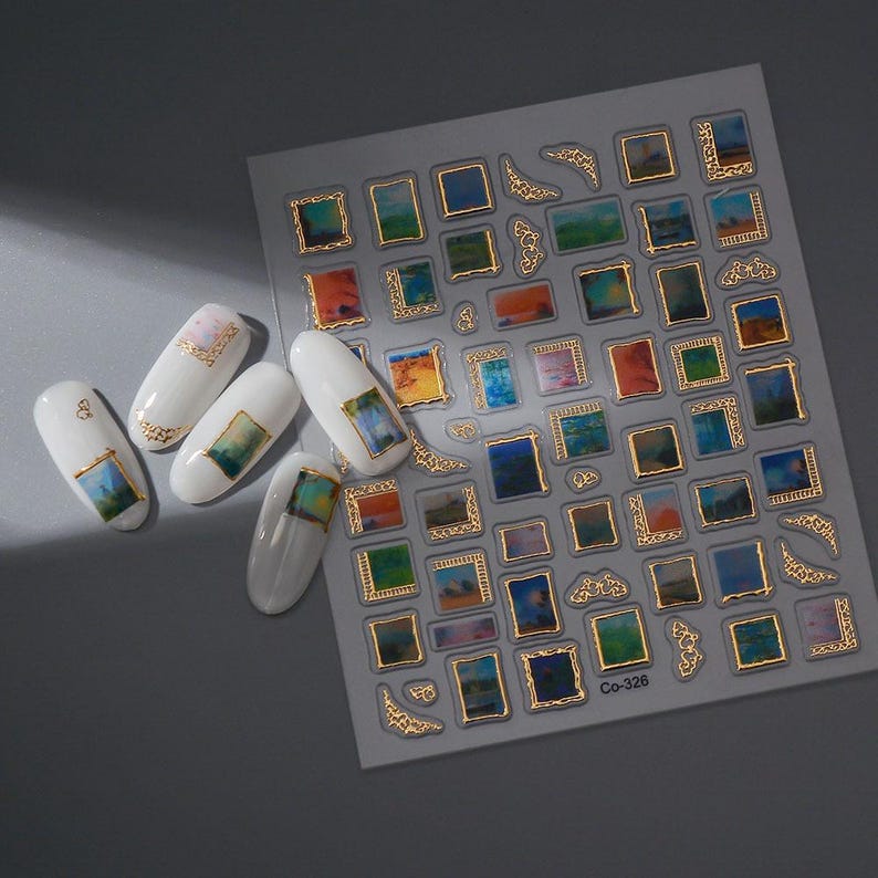 May include: Nail art stickers featuring miniature abstract paintings in gold frames. The sheet includes various sizes and shapes, with some applied to white nail polish. The paintings showcase a range of colors, including blues, greens, oranges, and yellows.