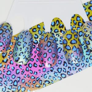 May include: A sheet of iridescent nail art decals with a leopard print pattern in shades of blue, pink, and yellow.