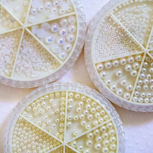 May include: Three round containers with multiple compartments filled with white pearl beads of various sizes.