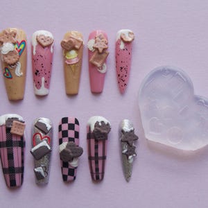 Könnte beinhalten: Zehn rosa und weiße Nagelspitzen mit verschiedenen Designs, darunter Eiscreme, Kekse und Karomuster. Eine transparente Silikonform ist ebenfalls enthalten.