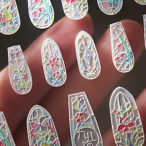 May include: Assortment of colourful nail art stickers featuring stained glass designs with floral and geometric patterns.