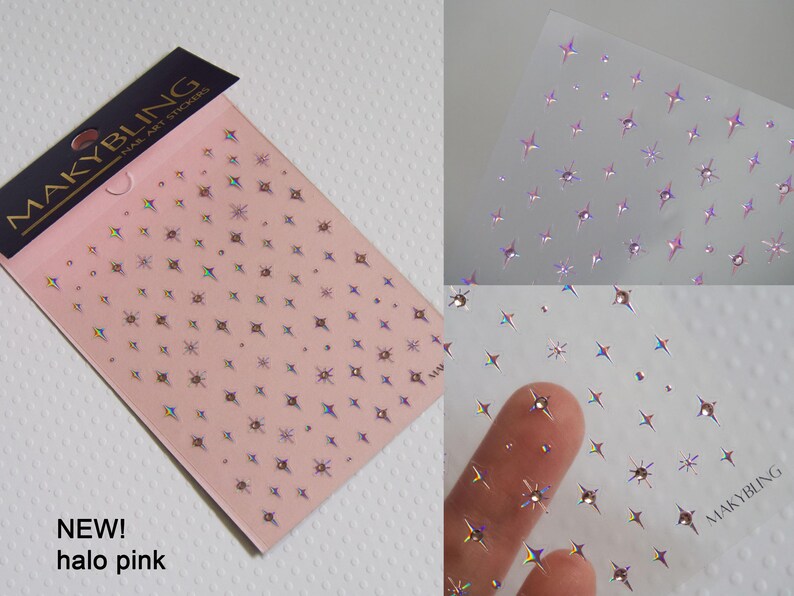 May include: Two sheets of nail art stickers with a holographic finish. The stickers feature a repeating pattern of small stars. The sheet on the left is pink and has the text "MAKYBLING" and "NEW! halo pink" printed on it. The sheet on the right is clear and has the text "MAKYBLING" printed on it.