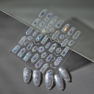 May include: Clear nail art stickers featuring stained glass window designs in various shapes and sizes. The stickers have iridescent and blue accents, with some applied to clear acrylic nails. The sheet is labeled "GO-248".