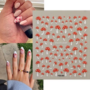 May include: A sheet of nail art stickers featuring red and white mushroom designs. The word "mushroom" is printed on the sheet. The image also shows manicured nails with mushroom designs.