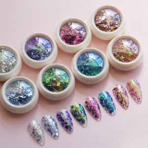 Peut inclure: Huit petits contenants ronds de paillettes irisées, chacun d'une couleur différente, disposés en rangée.  Sous les contenants, dix petites paillettes sur une surface rose.