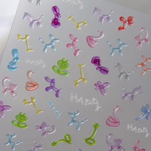 May include: A clear sheet with multiple colorful balloon animal shapes and the word "Happy" repeated several times. The sheet is designed for crafting and creating projects.