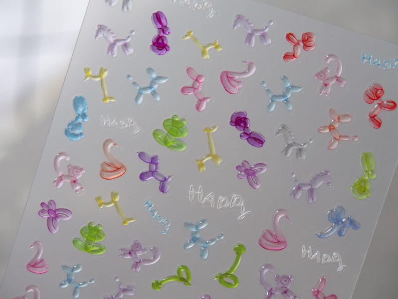 May include: A clear sheet with multiple colorful balloon animal shapes and the word "Happy" repeated several times. The sheet is designed for crafting and creating projects.