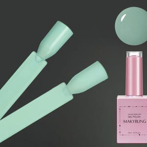 Puede incluir: Una botella de esmalte de uñas de gel verde claro con una tapa rosa. La botella está etiquetada "Wiped Soak Off Gel Polish Makybling 7.5ml 0.25 fl oz".