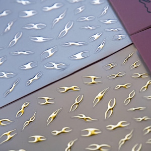 May include: Two sheets of nail decals with a flame design. One sheet has silver flames and the other sheet has gold flames.