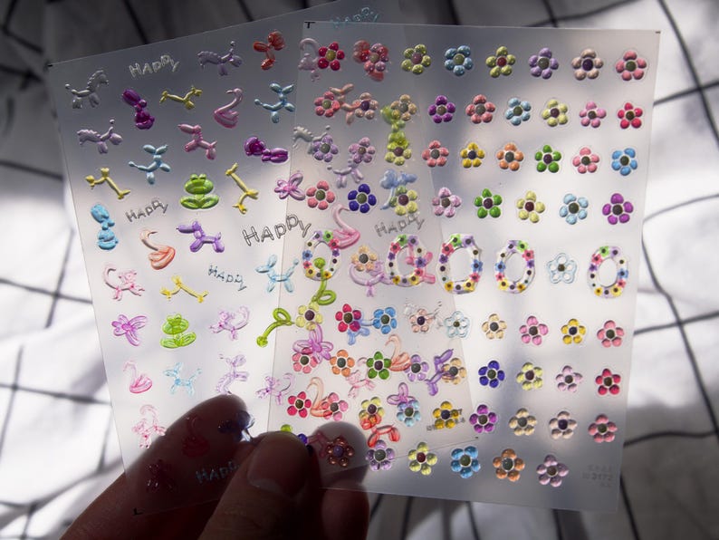 May include: A sheet of colorful stickers with various designs, including flowers, animals, and the word "Happy".