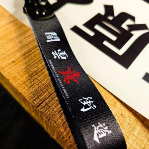 Puede incluir: Una taza de cerámica blanca con un asa negra y el texto "But First, Coffee" en negrita negra. La taza se encuentra sobre un fondo neutro, resaltando su diseño simple.