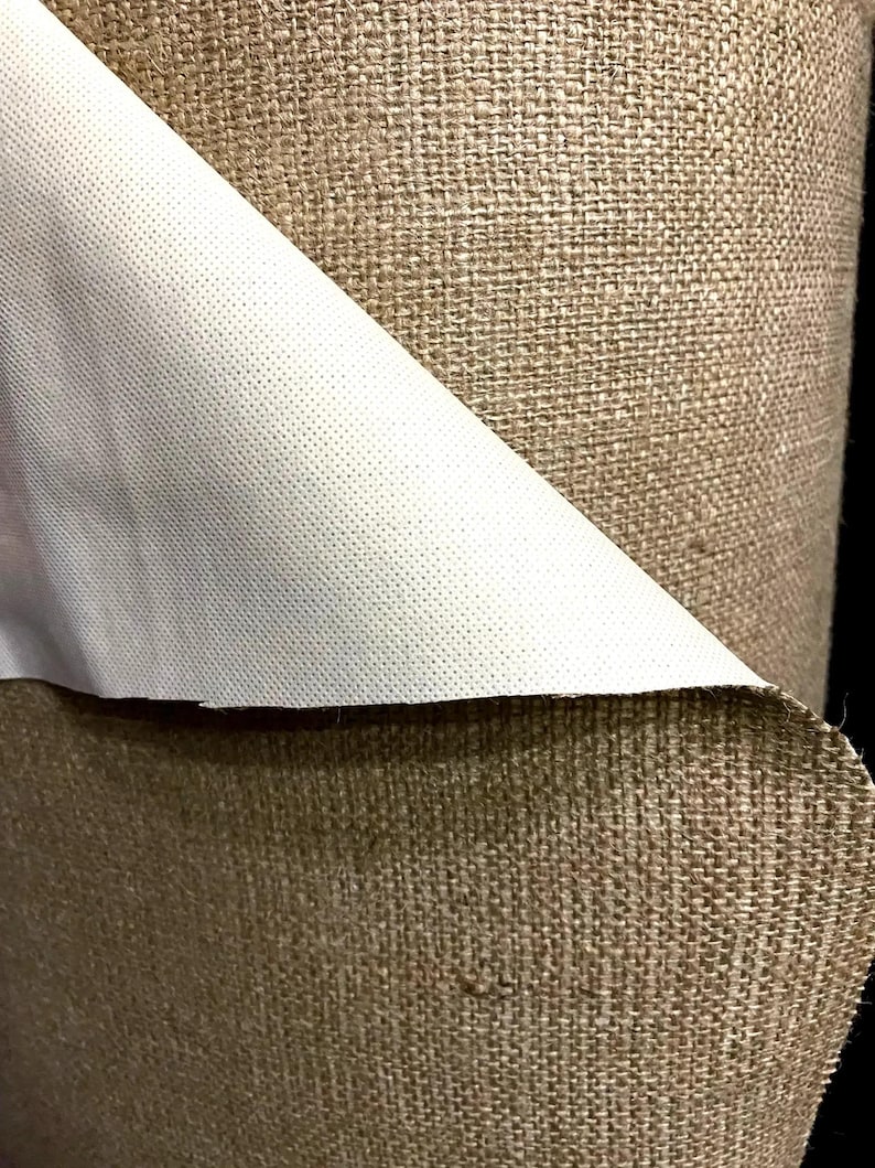 May include: Close-up of a roll of brown burlap fabric with a white backing. The fabric has a woven texture and is ideal for crafting projects.