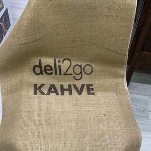 May include: A brown burlap sack with the text "deli2go KAHVE" printed on it.
