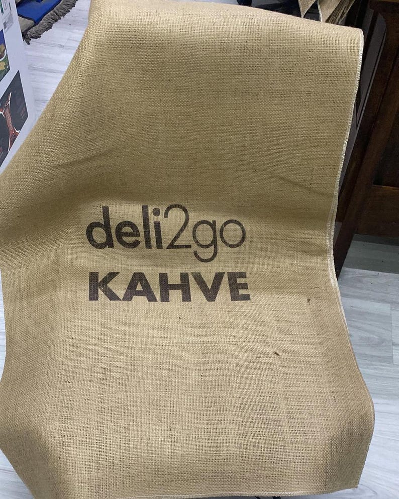 May include: A brown burlap sack with the text "deli2go KAHVE" printed on it.