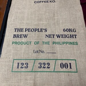 May include: A brown burlap sack with black text that reads "PARA SA MASA COFFEE KO. THE PEOPLE'S BREW 60KG NET WEIGHT PRODUCT OF THE PHILIPPINES Lot No. 123 322 001".