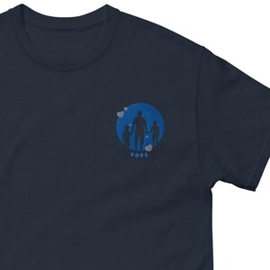 May include: Navy blue t-shirt with a blue circle graphic of a father and two children holding hands. The text "Pops" is below the graphic.