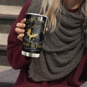 May include: A black and gold stainless steel tumbler with the text "Onyx Storm" and "Brave the Dark" and a graphic of a dragon. The text "I will not fear the fading light, I will save him." is also on the tumbler.