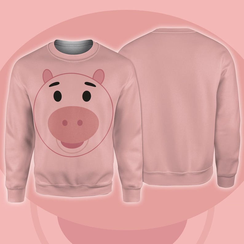 Pode incluir: Um moletom rosa claro com o rosto de um porco de desenho animado na frente. O rosto do porco tem olhos pretos, um focinho rosa e orelhas rosas. A parte de tr&aacute;s do moletom &eacute; de cor rosa claro lisa.