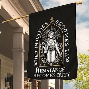 May include: Black flag with a gold-outlined illustration of Lady Justice, holding scales and a sword, with the text "WHEN INJUSTICE BECOMES LAW RESISTANCE BECOMES DUTY". The flag is hanging on a gold pole.