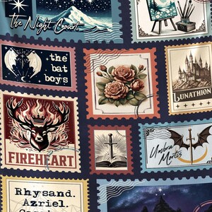 May include: A navy blue throw blanket featuring a collage of postage stamp designs. The stamps depict various illustrations, including a mountain scene, a castle, roses, and text that reads "The Night Court", "Fireheart", and "Umbra Mortis".