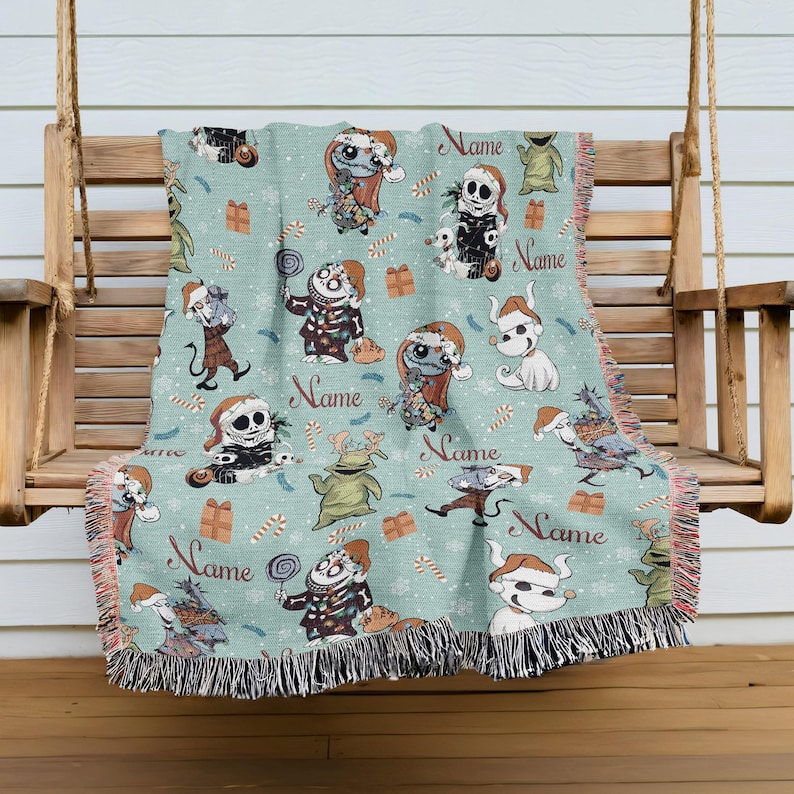A colorful throw blanket with various cartoon characters and holiday-themed designs, including Santa Claus, a skeleton, and other festive elements, is hanging on a wooden bench.