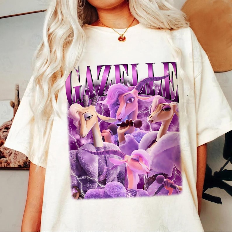 A person wearing a white t-shirt with a graphic design featuring purple and pink characters, including a unicorn and a dragon.